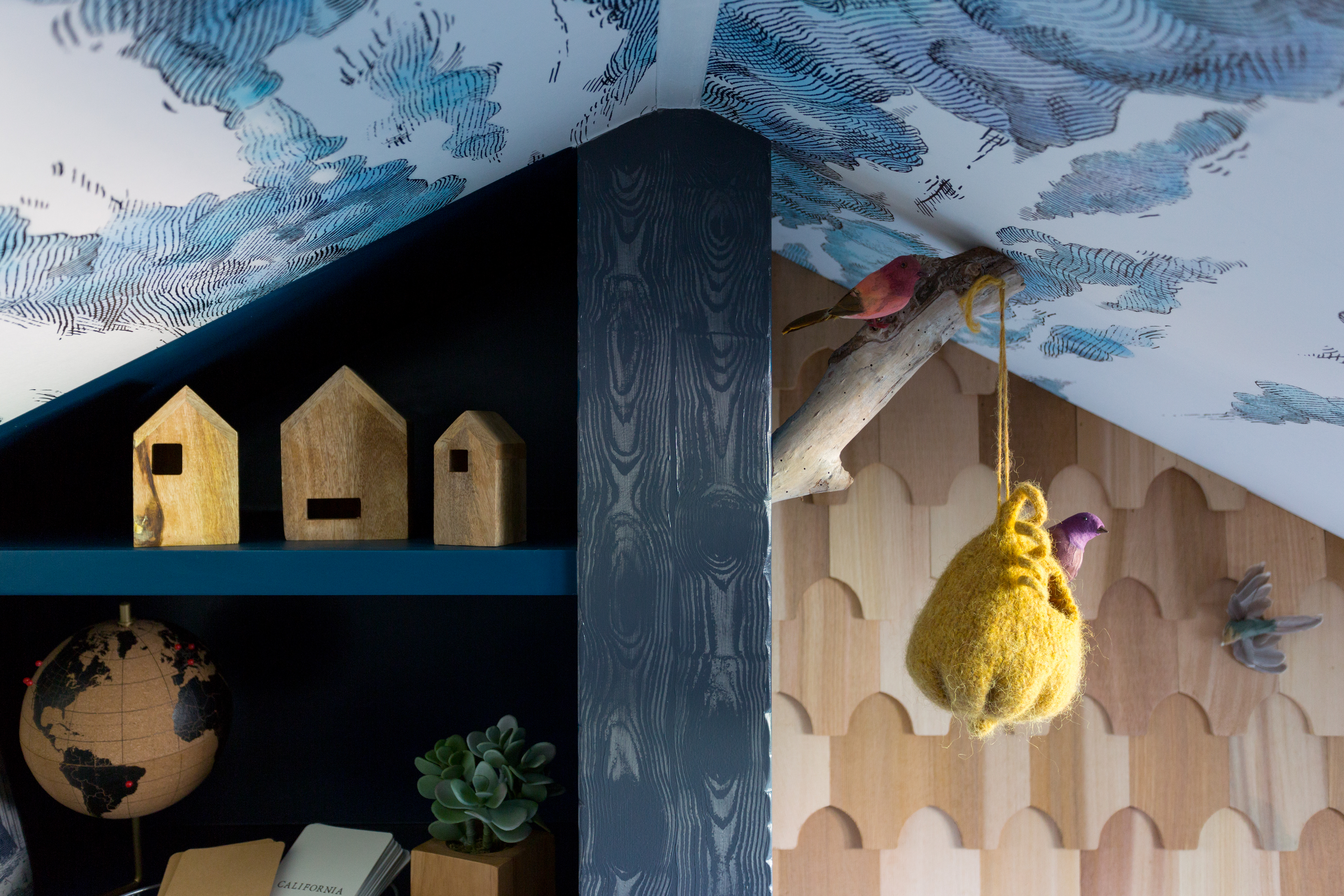 Bookshelves in attic playroom with cloud wallpaper on the ceiling