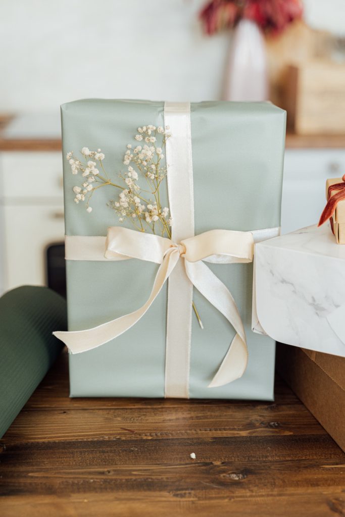 mint green Christmas present with white ribbon and white flowers